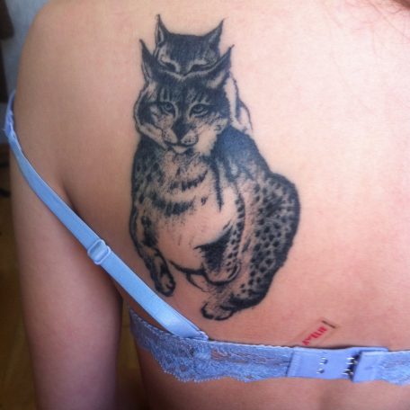 Татуировка на лопатке у девушки в виде двух рысей